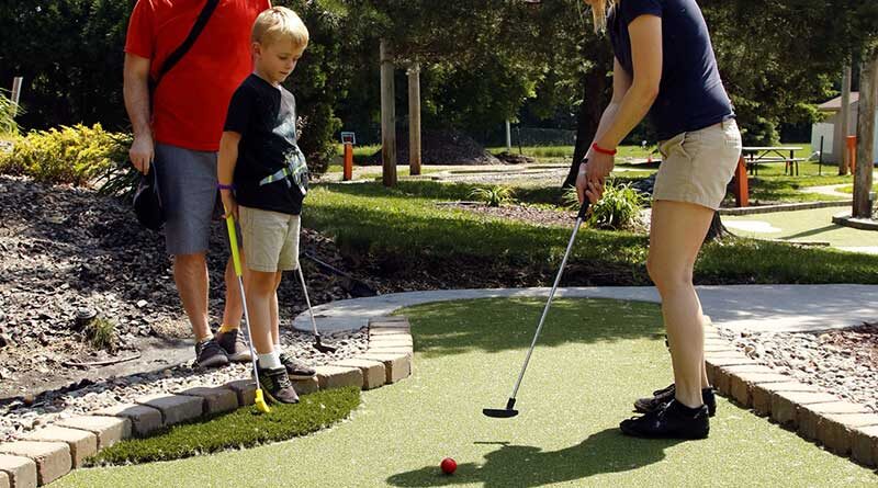 Dad and son watch mom putt at one of the new mini golf holes at Veterans Memorial Park in Richfield, Minnesota. Wheel Fun Rentals, operators of the course, engaged Adventure Golf & Sports (AGS) to renovate the mini golf course using their timesaving, economical and eco-friendly Modular Advantage® Mini-Golf system.